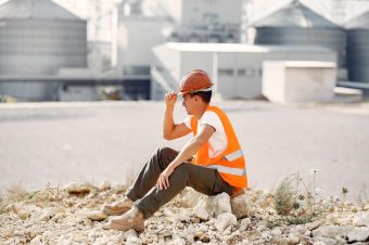 Engineer near the factory. Man in a helmet. Inspector looks at the building.