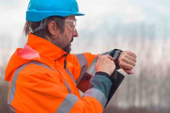 Forestry technician checking up on his smart watch while working outdoors in forest